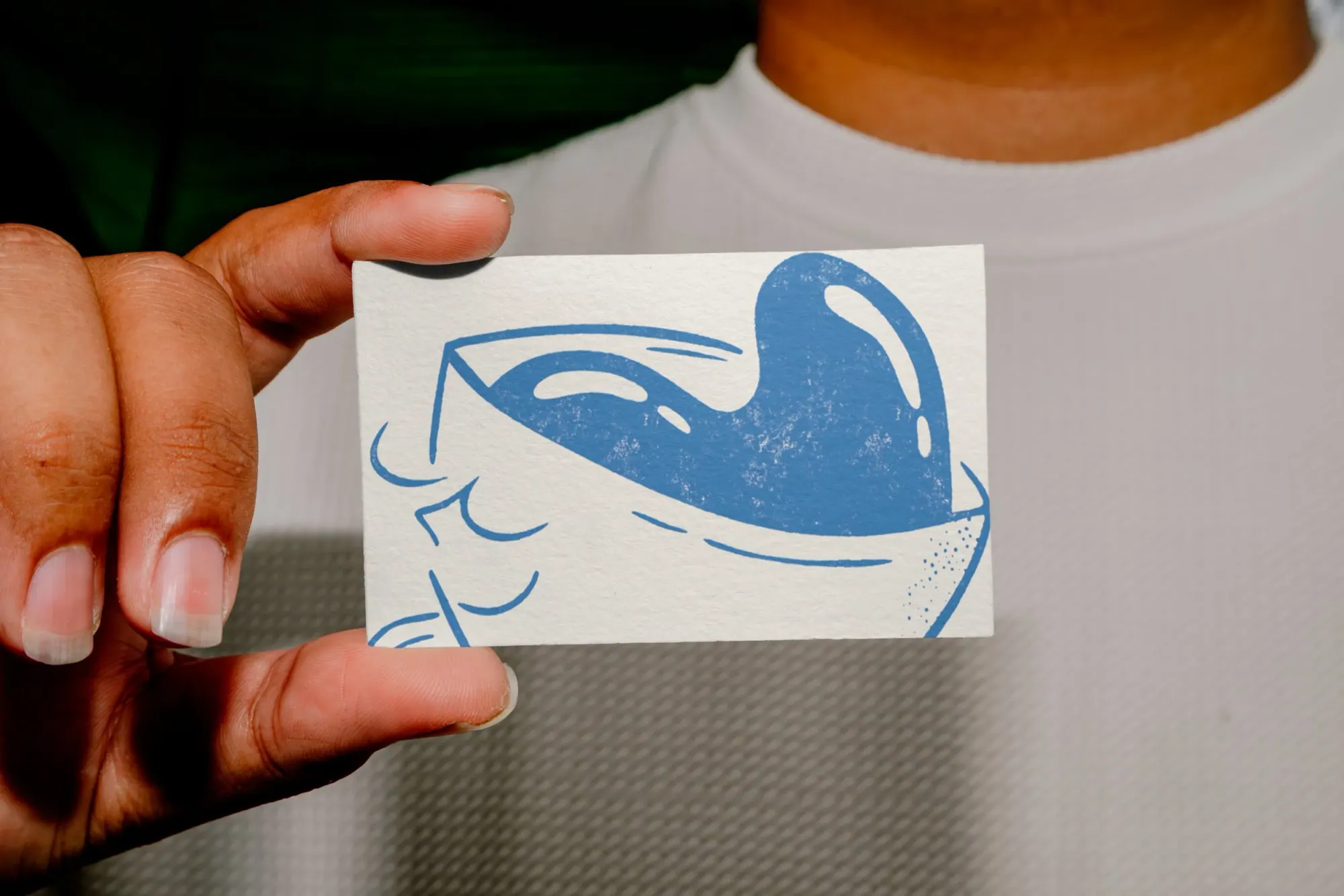 Une personne tient une petite carte ou affiche avec une illustration bleue d'une tasse de café.